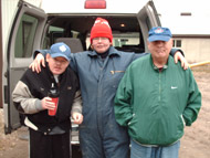 Three men standing together beside a van